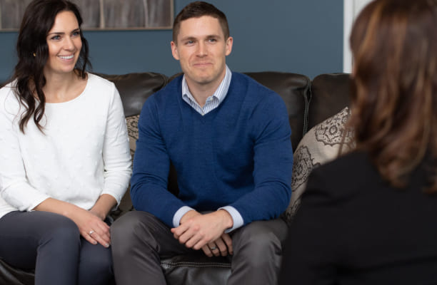 A young couple sits and speaks with an Investors Associated employee, whose back is facing the camera.