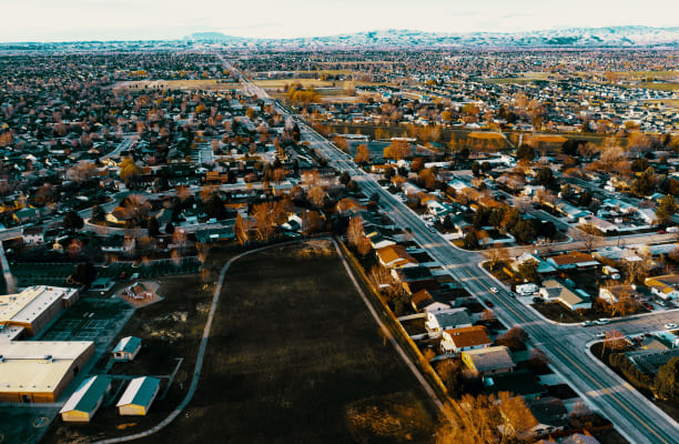 A drone image of a suburban neighborhood with many houses, trees, and a park.