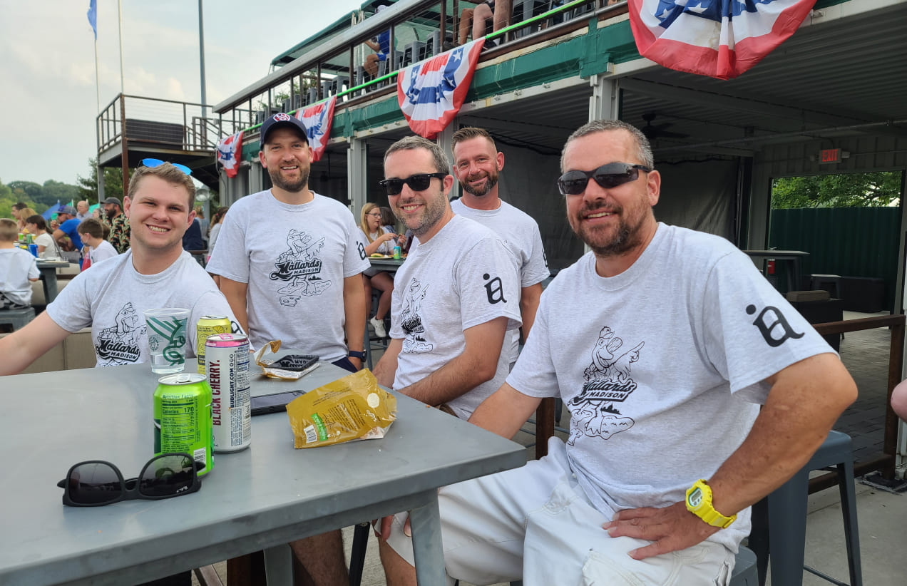 Members of the Investors Associated team sit at a hightop table at a Madison Mallards game.