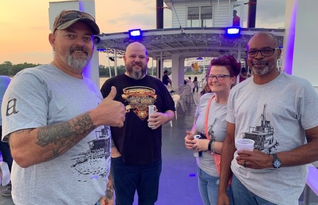 Members of the Investors Associated team pose for a photo during a team outing on a boat at sunset.