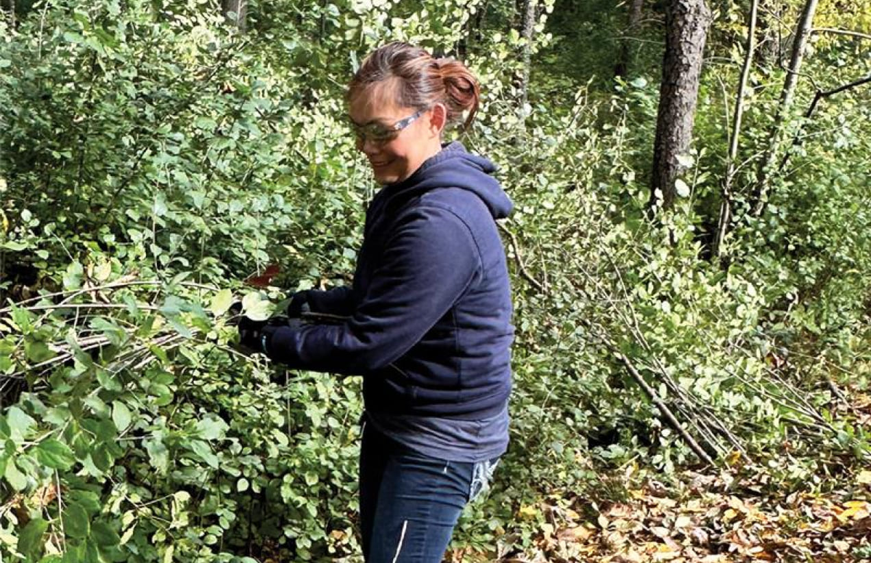 A member of the Investors Associated team clears brush while volunteering