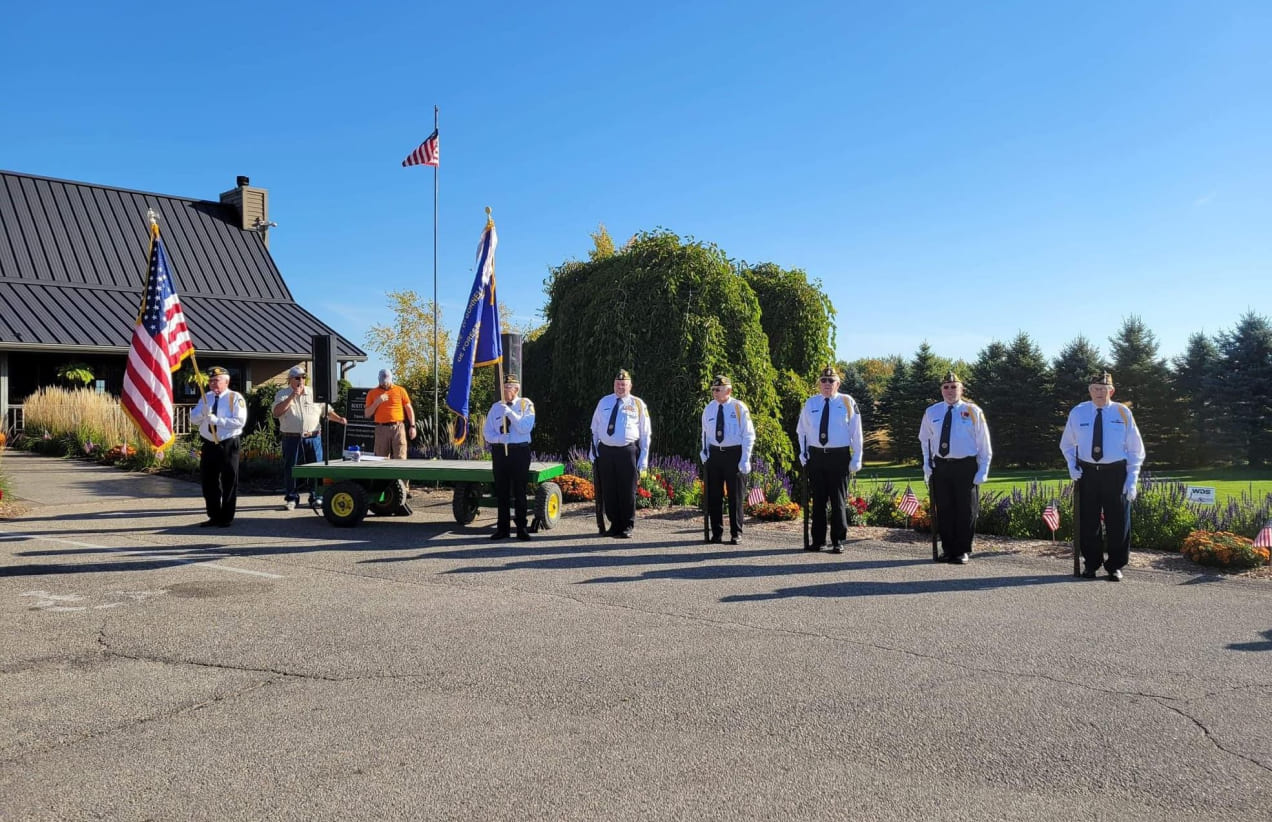 Veterans in uniform stand with flags at an event attended by members of the Investors Associated Community Relations Committee.