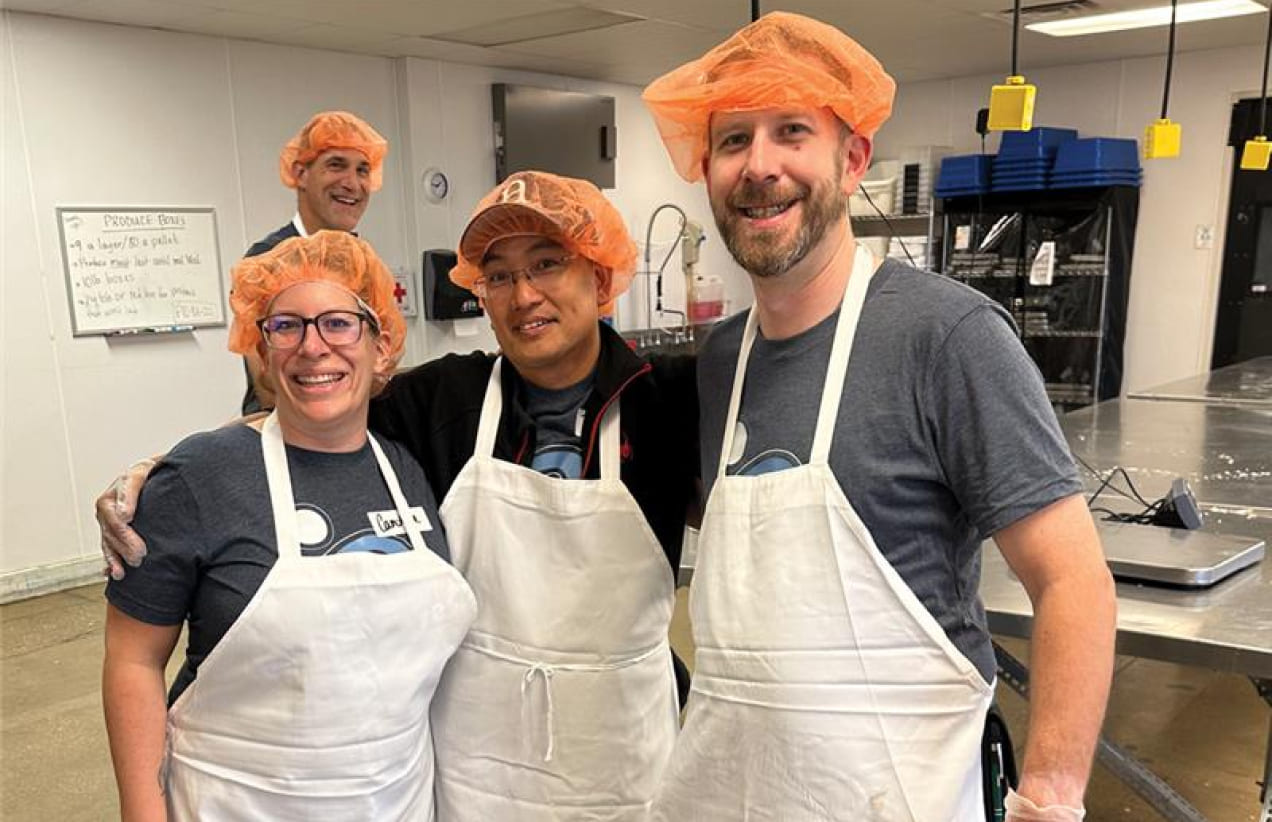 Members of the Investors Associated team wear hairnets and aprons while volunteering.
